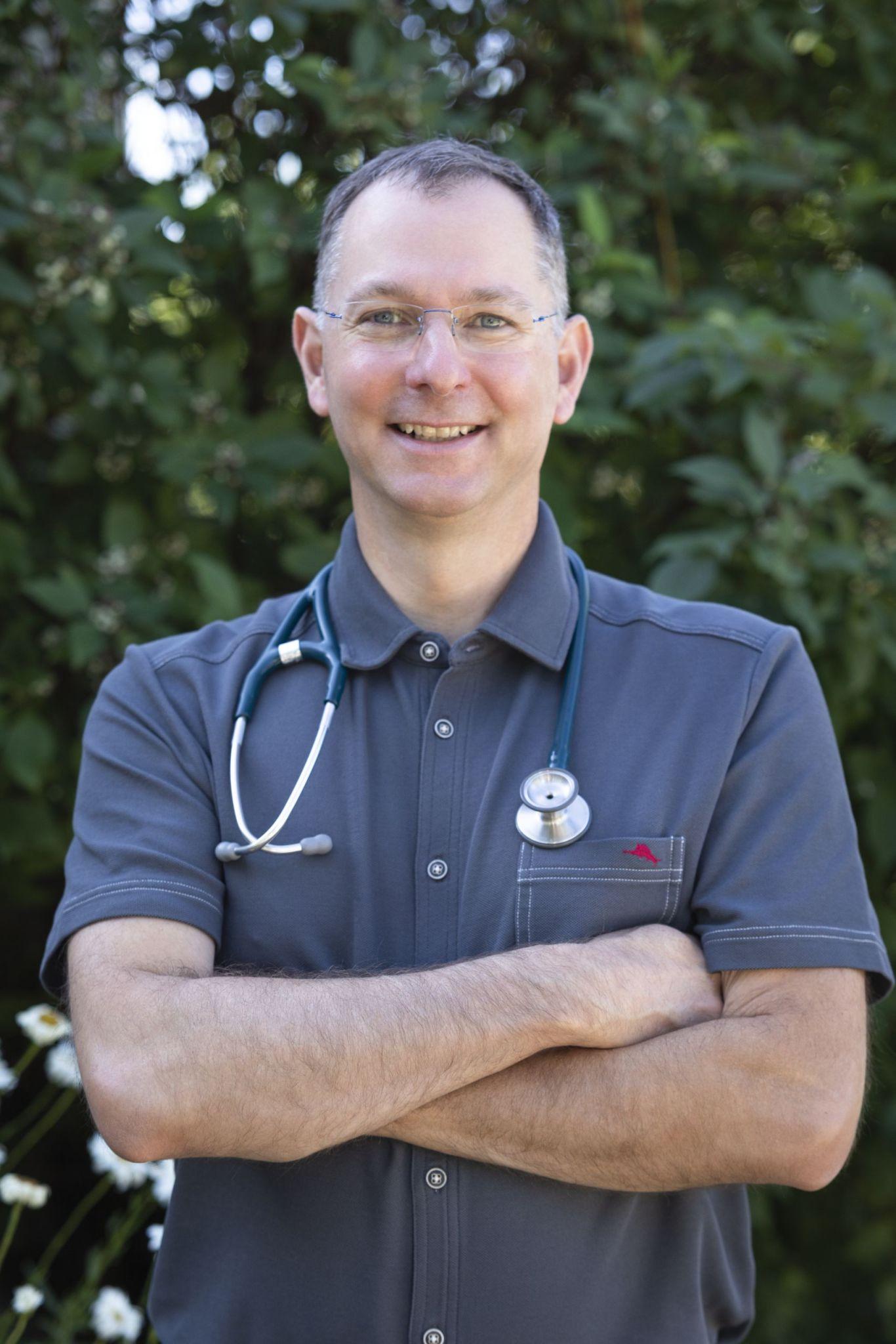 A man with his arms crossed wearing a stethoscope.