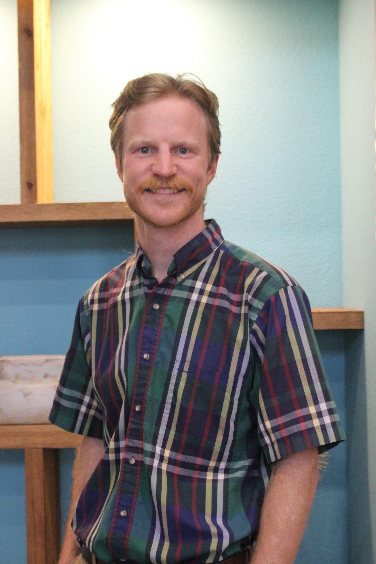 A man with red hair and beard wearing a plaid shirt.