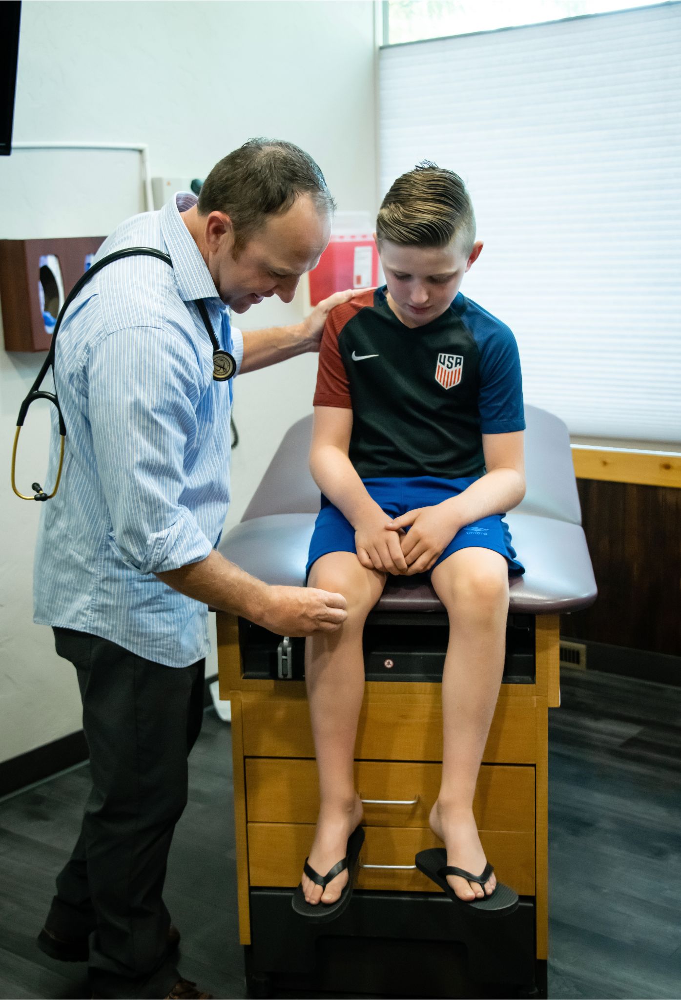 A doctor examines the knee of a young boy.