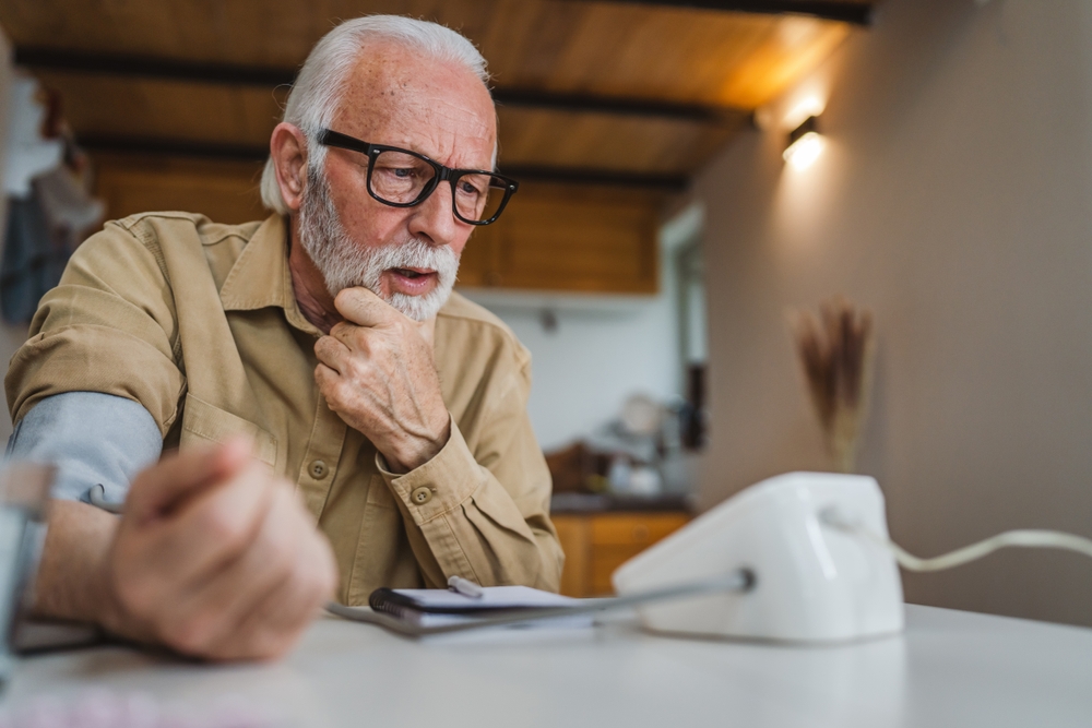 One man senior caucasian male with beard use blood pressure device to check and measure results while sit at the table at home alone real people copy space health care concept read bad results