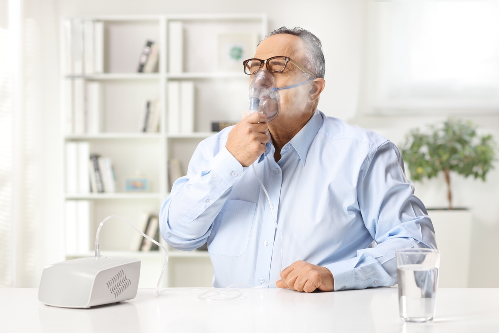 Man treating chronic respiratory illness with a nebulizer
